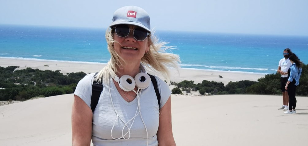 Elen with sun glasses, sand dunes and sea in the back ground.